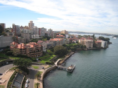 From the north end of the Sydney Harbour Bridge sidewalk, this view of homes is typical of everything near downtown, with the ground rising from the water and many floors of many buildings soaking up the sun and views.