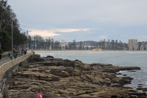 Manly Beach is the town and the sandy ocean face, a small line of pines, a walkway to explore, and a bustling Saturday marketplace.